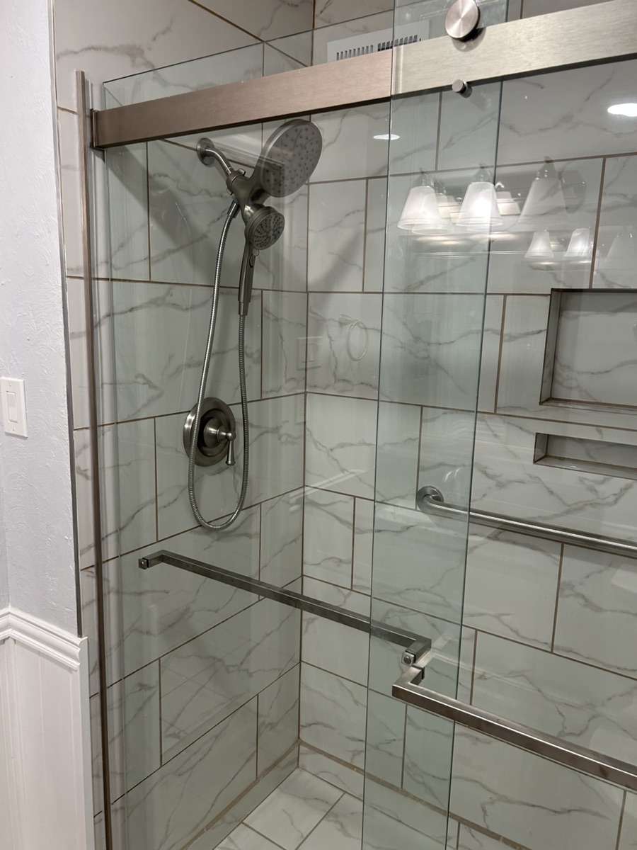 Finished shower with tile, glass door, and grab bar