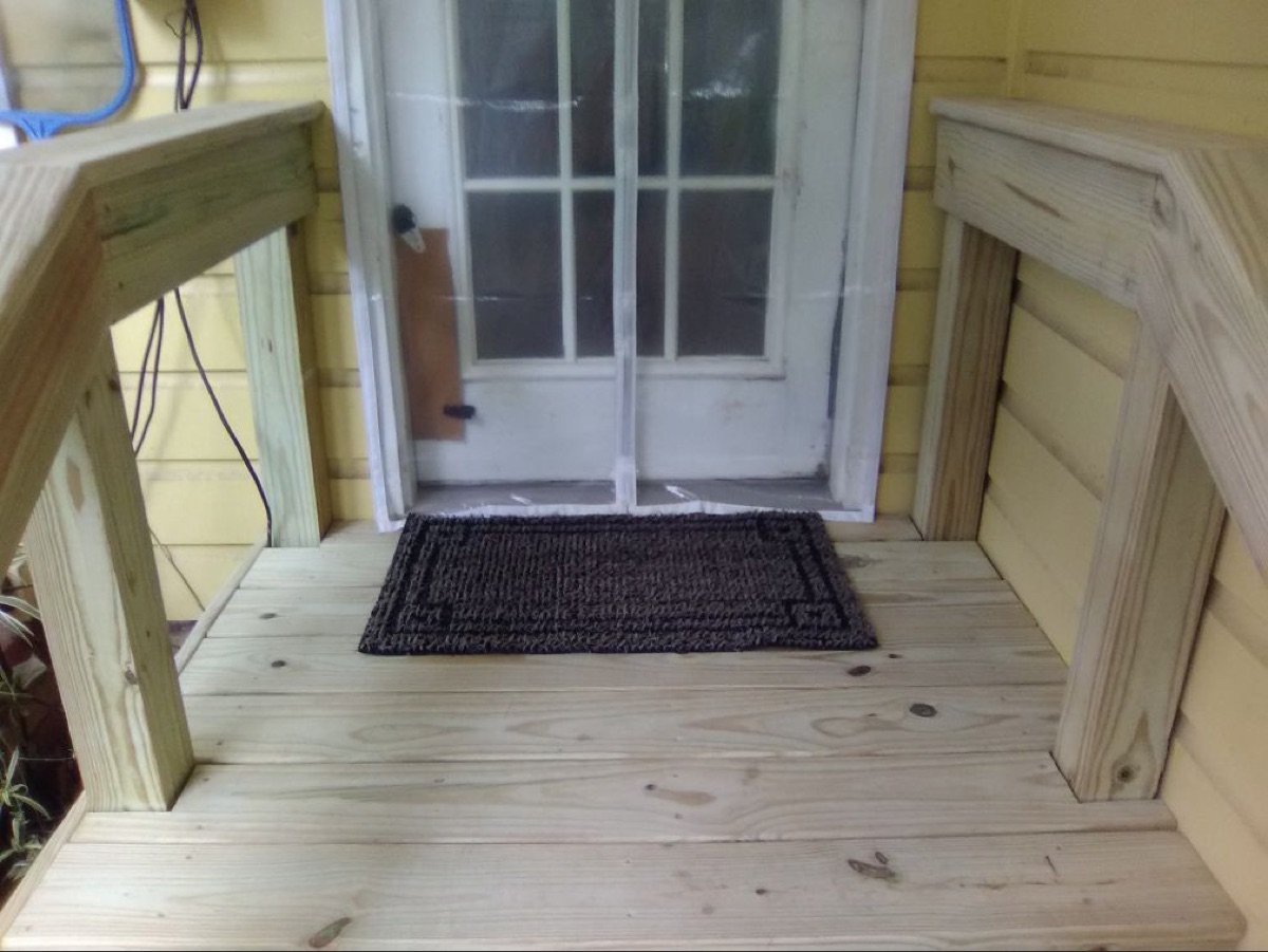 Finished wood porch steps and handrails at a back door